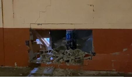 Exterior brick wall of a Detroit liquor store with a sizable hole in it from what is assumed to be an attempted robbery.