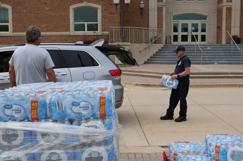 Residents get water at distribution site in Macomb Township after water main break.