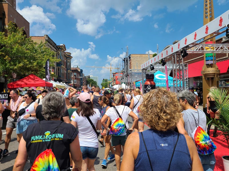 Dozens of people walk through a street during a festival