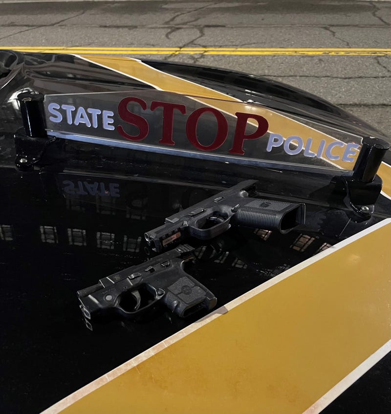 Two seized pistols on the hood of a state police car