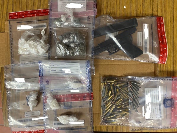 Evidence seized in a drug bust laid out on a table, including fentanyl, cocaine, meth, a pistol and bullets.