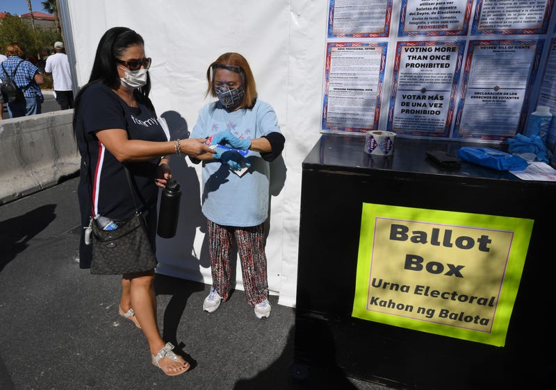 A voter drops off her 2024 Presidential election ballot to a mail-in location in Las Vegas 