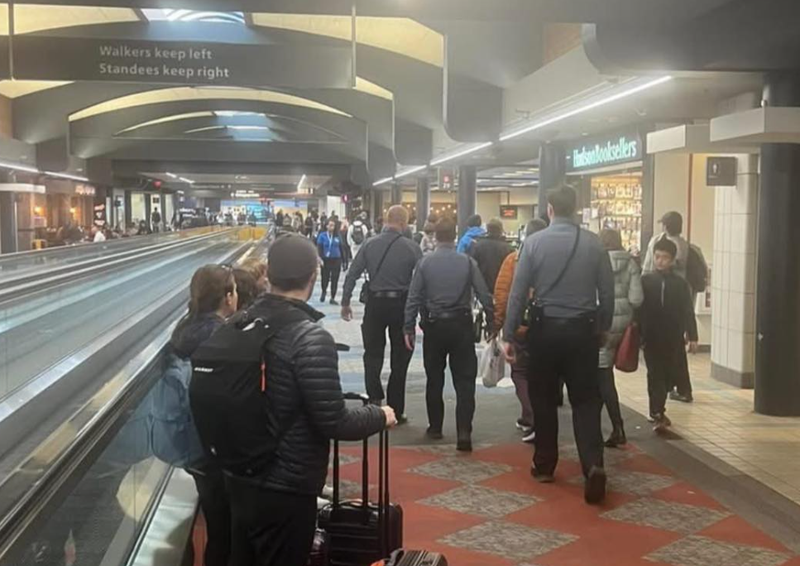 Marc Fogel surrounded by officers walking at Pittsburgh International Airport