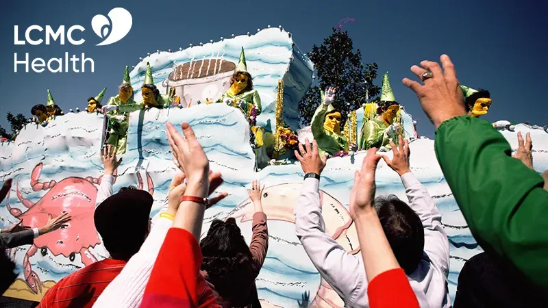 Crowd reaching for parade float with LCMC Health logo