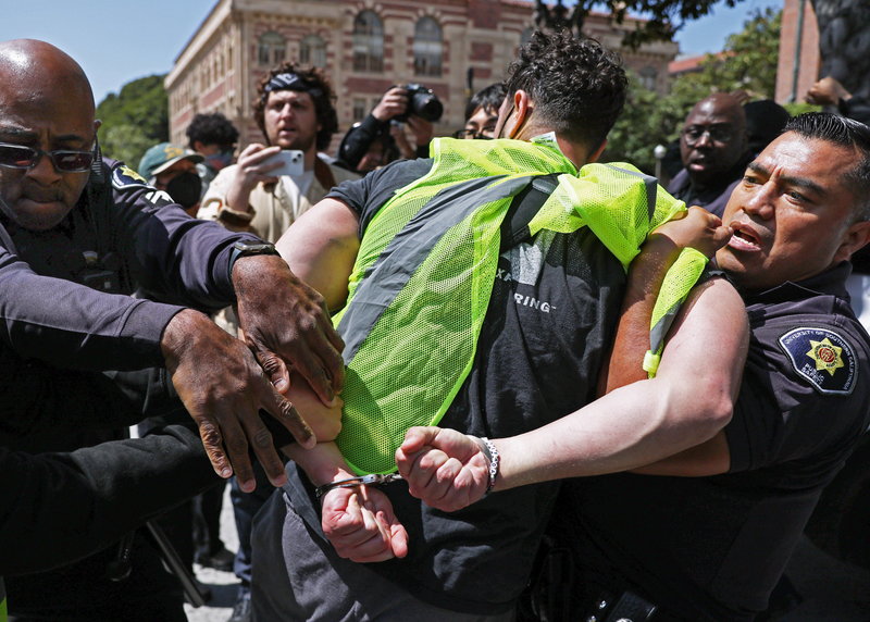 LOS ANGELES, CALIFORNIA - APRIL 24: USC police officers detain a pro-Palestine demonstrator during clashes after officers attempted to take down an encampment in support of Gaza at the University of Southern California on April 24, 2024 in Los Angeles, California. Pro-Palestinian encampments have sprung up at college campuses around the country recently.
