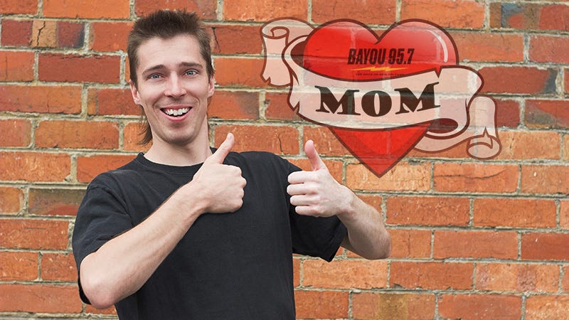 man with mullet haircut and 2 thumbs up in front of brick wall with mullet tattoo design