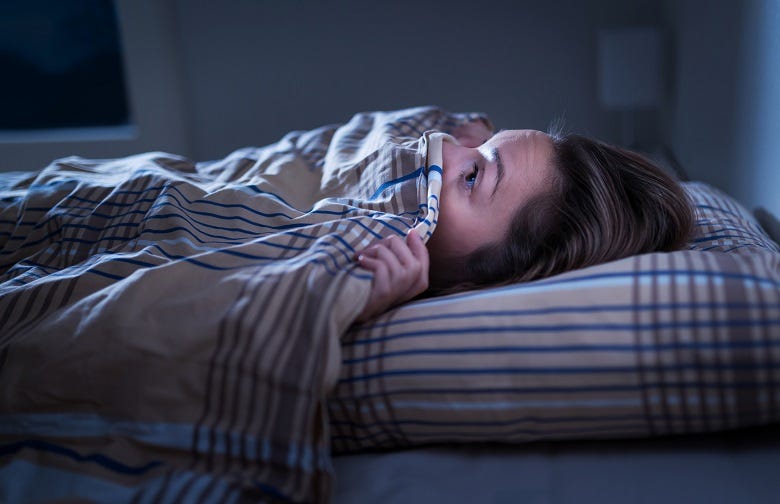 woman in bed with covers pulled over face