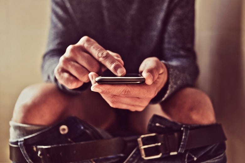Guy on phone sitting on toilet