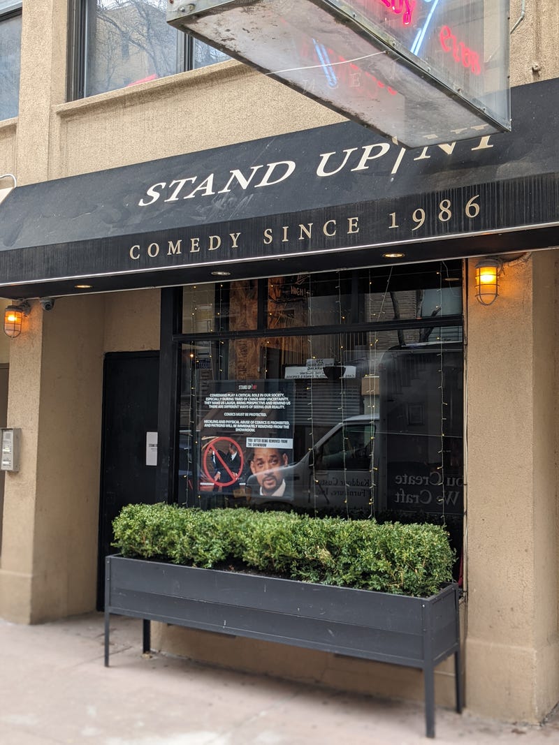 The sign says "comics must be protected" and warns patrons against assaulting comedians