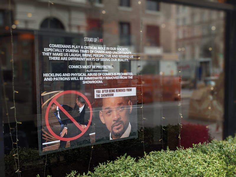 The sign includes a photo of a teary-eyed Smith accepting his best actor award shortly after the slap, along with the warning: “You: after being removed from the showroom"