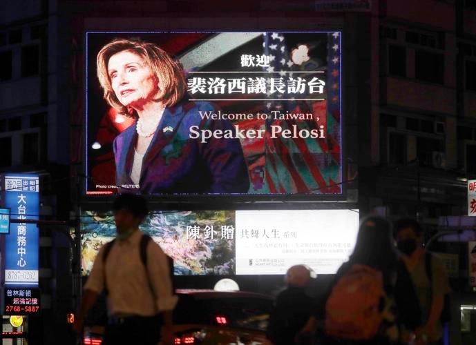 People walk past a billboard welcoming U.S. House Speaker Nancy Pelosi, in Taipei, Taiwan, Tuesday, Aug 2, 2022