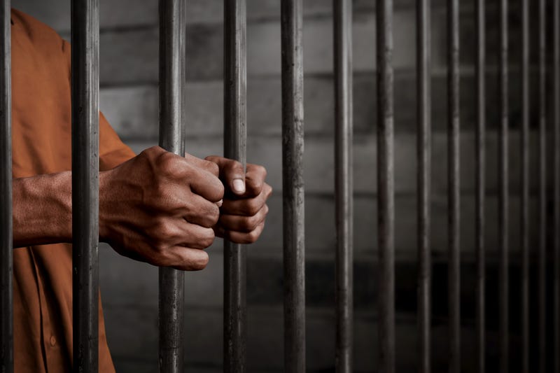 Male prisoner holding onto bars inside a cell