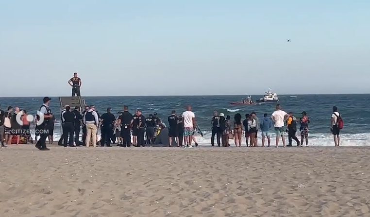 Police and beachgoers observe official sea vessels searching for two missing teen swimmers at Jacob Riis Park in Queens on Friday.