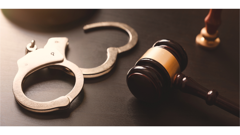 Handcuffs next to a judge's gavel