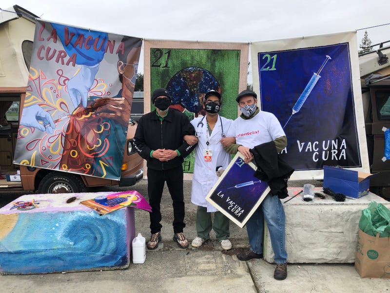 Artists and healthcare workers pose in front of banners addressing vaccine fears