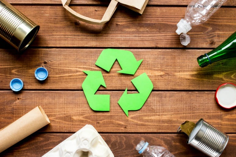 Eco concept with recycling symbol and garbage on wooden table background top view