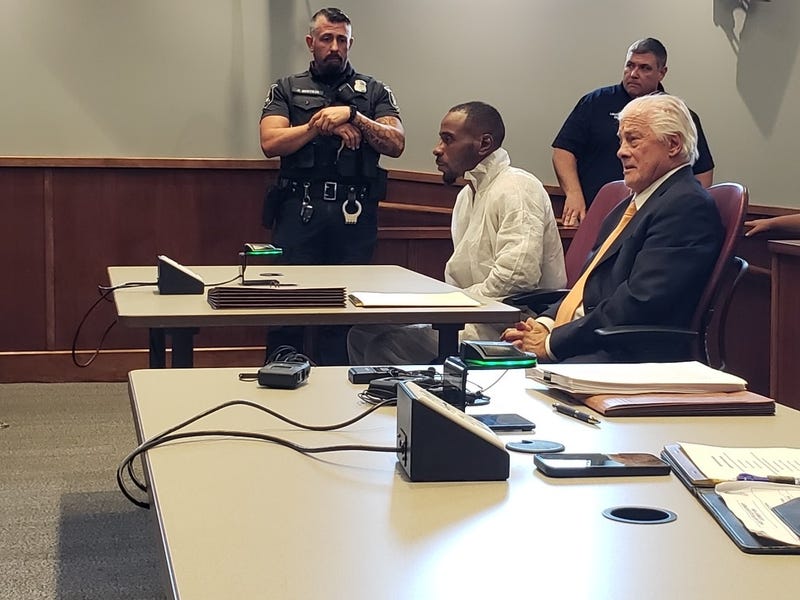 Ladamien Hill, left in white shirt, is seated beside his attorney in court.