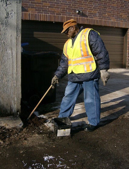 A Streets and Sanitation worker baits a rodent trap. 