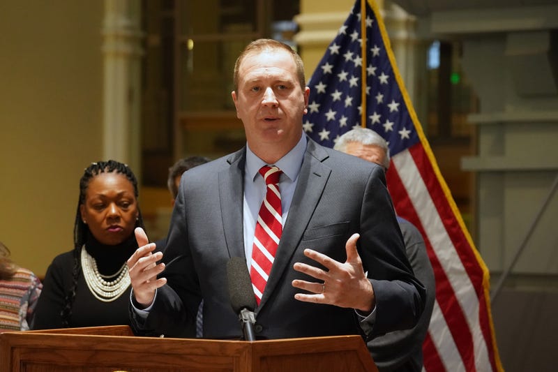Eric Schmitt stands at a podium in front of an American flag.