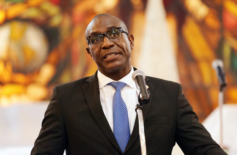 Lewis Reed stands at a podium in front of a blurred background.