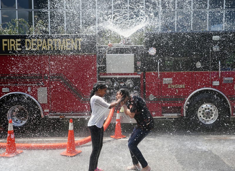 Children try to beat the 98 degree heat by running through a water spray provided by the St. Louis Fire Department on Day 2 of the Fair St. Louis in St. Louis on Monday, July 4, 2022.