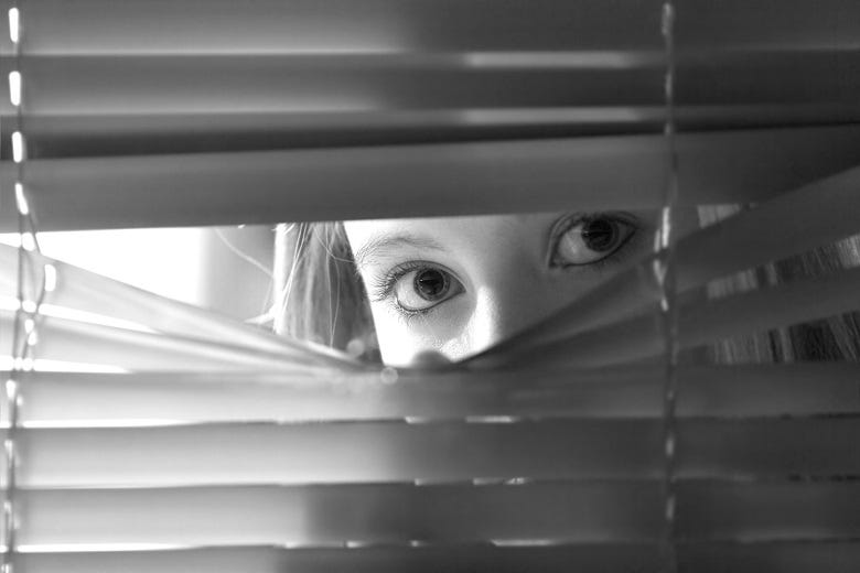 woman looking through blinds 