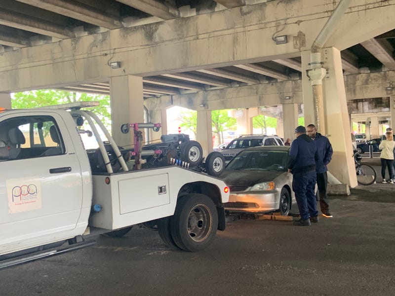 A PPA tow truck tows one of the cars operated on by illegal street mechanics under I-95 in Pennsport.