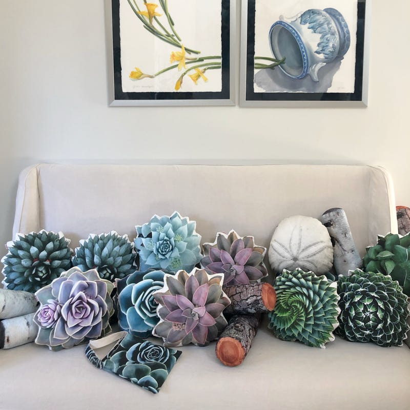 Plant pillows are displayed on a couch.