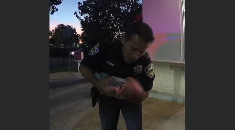 Officer Garcia performing CPR on a baby boy outside In-N-Out Burger.
