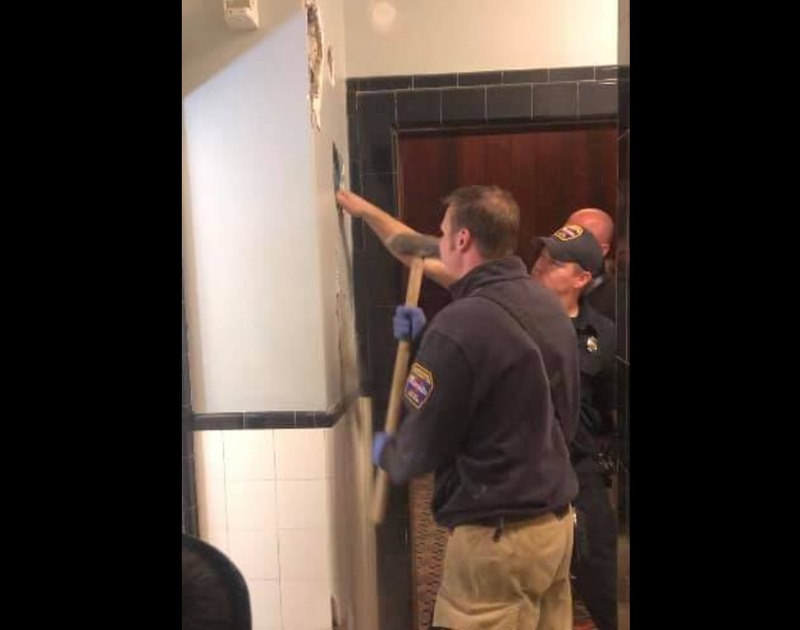 Firefighters breaking hole into wall