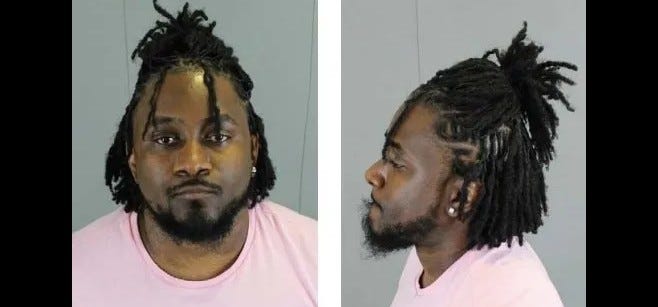 Black man in 30s wearing pink shirt with beard 