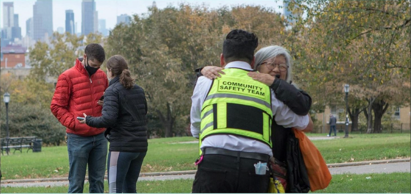 A community worker and elderly woman embrace