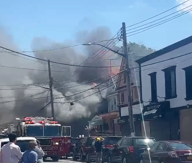 Firefighters are battling a five-alarm fire at a home in Queens that has reportedly spread to other buildings.