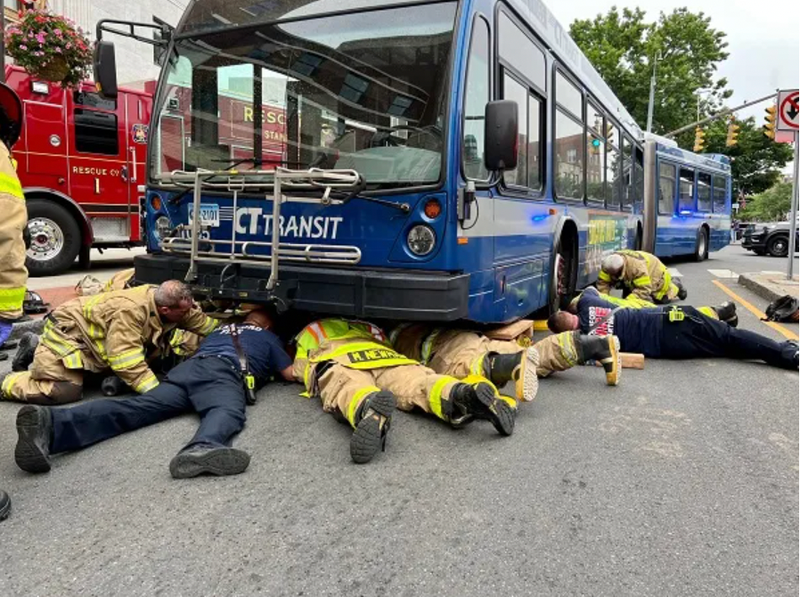 Firefighters rescuing woman trapped under bus