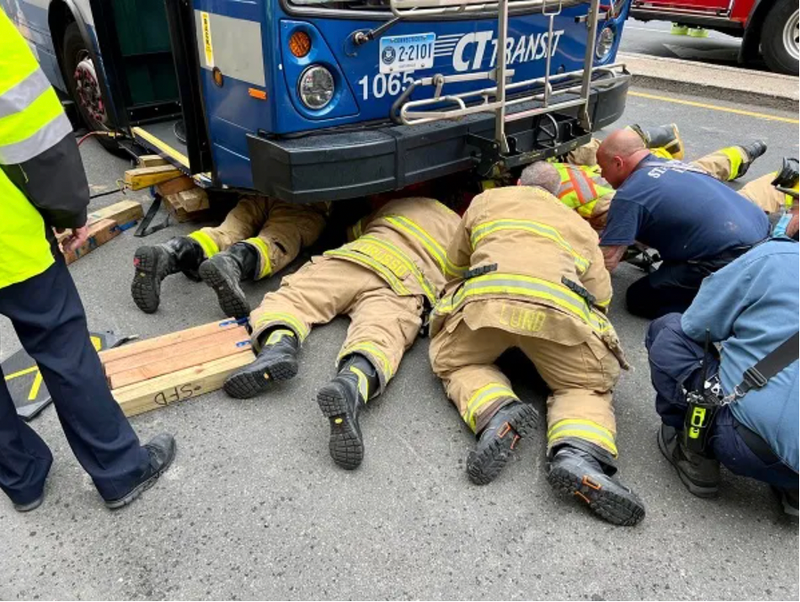 Firefighters rescuing woman under bus