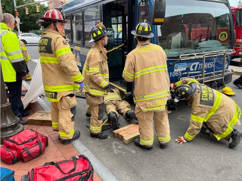 Firefighters rescuing woman from underneath bus