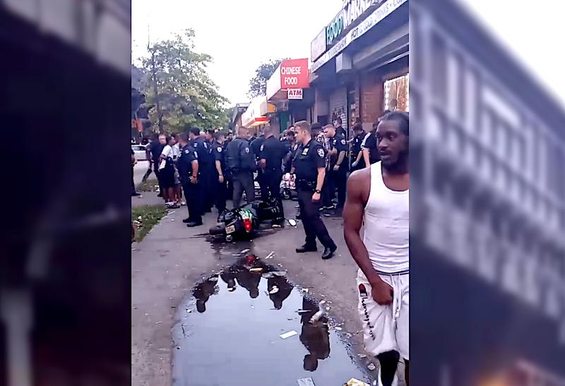 Police officers and bystanders at the scene of a shooting in Brownsville on Sunday night