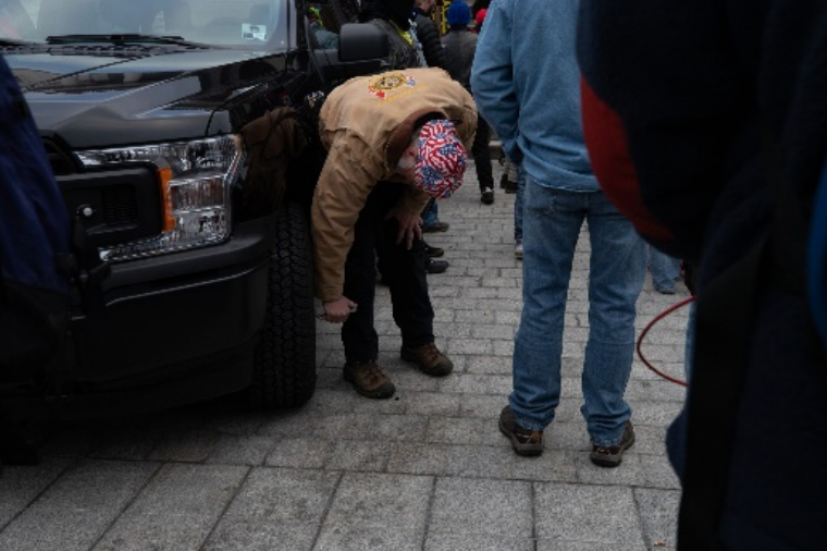 Young popping the tire of a government vehicle. 