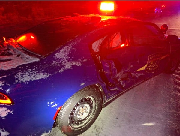 A Michigan State Police car with the side crushed in, airbags deployed and covered with snow.
