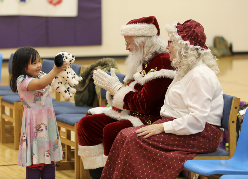 A little girl shows off her new toy to Santa
