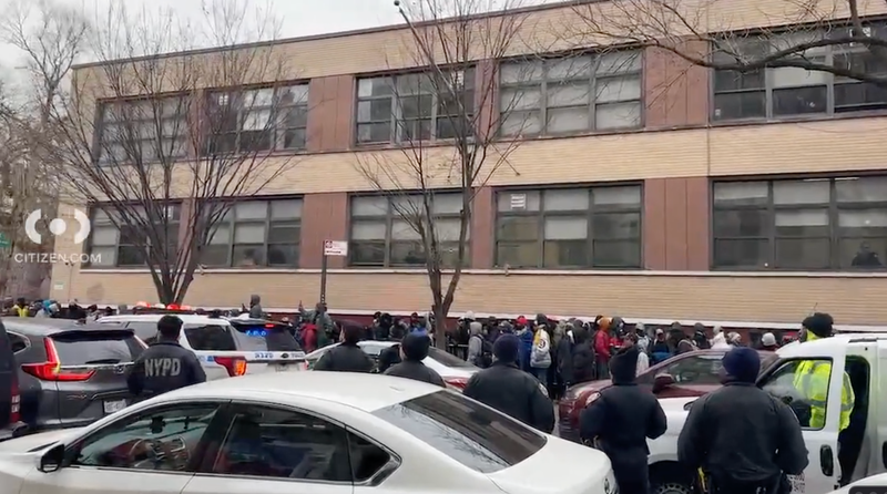 A large crowd of migrants wait outside an intake center in the East Village on Saturday; the NYPD is also on the scene.