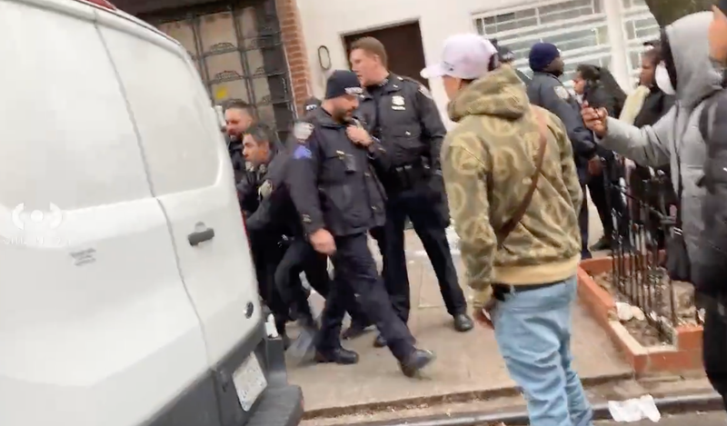 NYPD officers struggle with a hand-cuffed man outside of a migrant intake center in the East Village on Saturday morning.