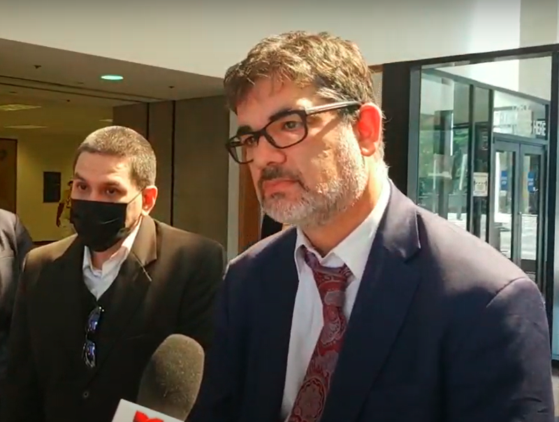 Two men, Joshua Tepfer and Arthur Almendarez, speak to reporters