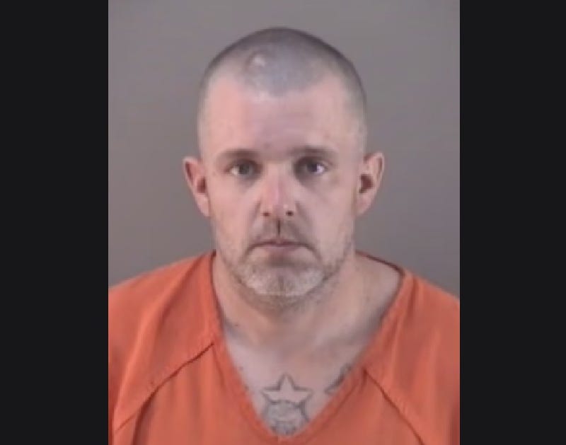 Middle-aged white man frowning in orange v-neck