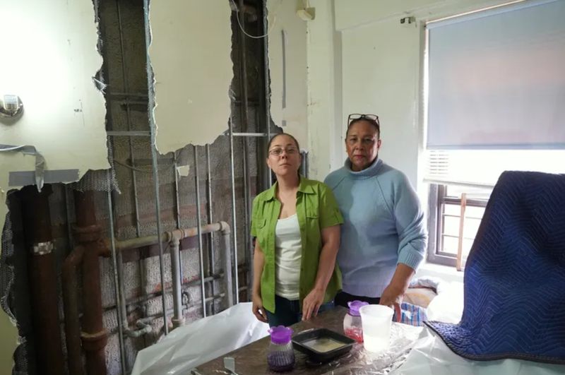 Two NYCHA residents stand in front of a destroyed wall in their apartment during a visit from Councilmember Carlina Rivera. The Public Advocate's office described NYCHA as the "overall worst landlord in New York City" in the 100 worst landlords list of 2022 list.