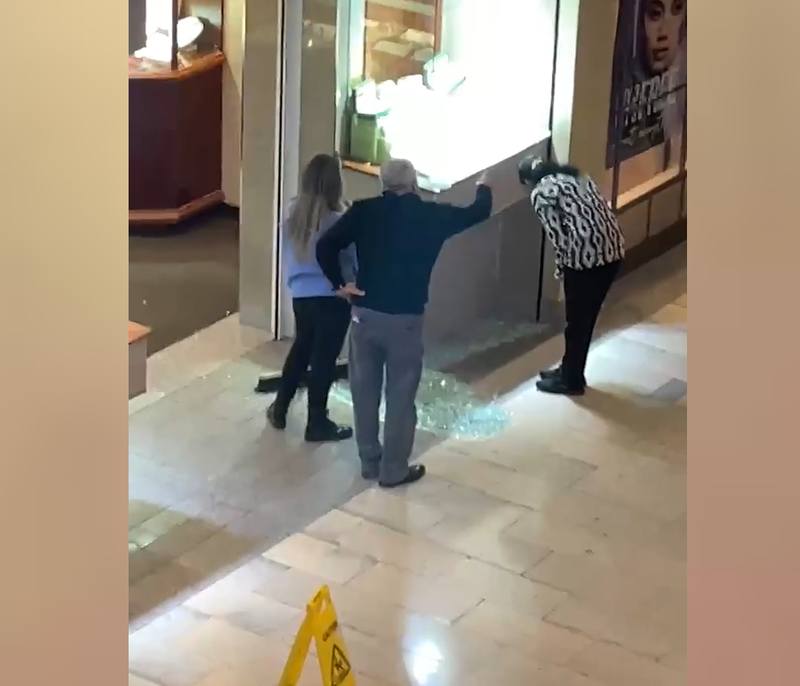 Bystanders examine the smashed display case at the Staten Island Mall.