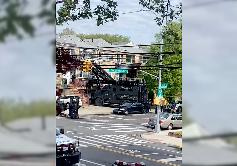 An armored vehicle extended some type of ladder to the home