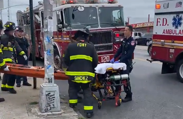 EMS and other FDNY personnel work to transport a gurney with one of the teenagers into an ambulance.
