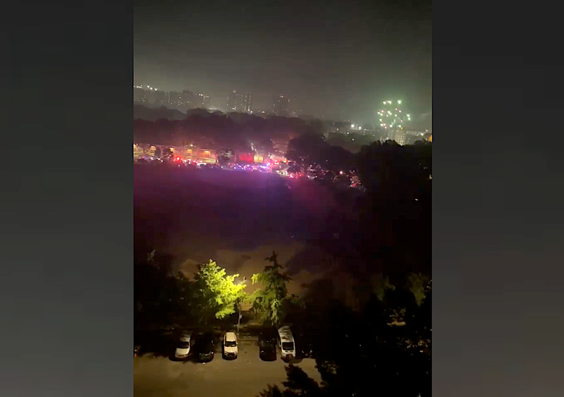 The lights of NYPD vehicles are seen in the Soundview section of the Bronx as fireworks go off in the distance