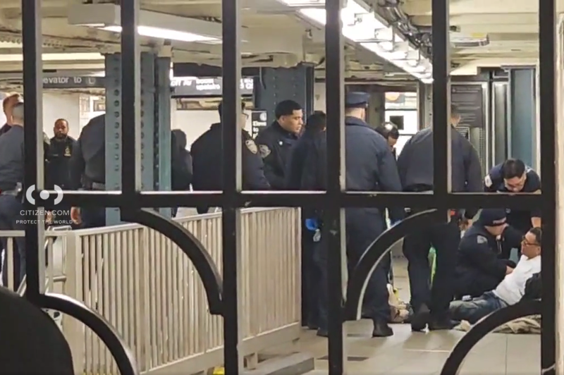 Police are seen attending to a man at the Myrtle–Wyckoff Avenues station around the time of the stabbing on Sunday evening